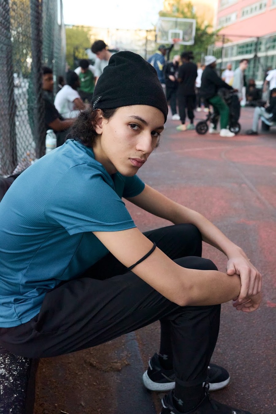 Seated portrait in a blue T-shirt at the basketball court