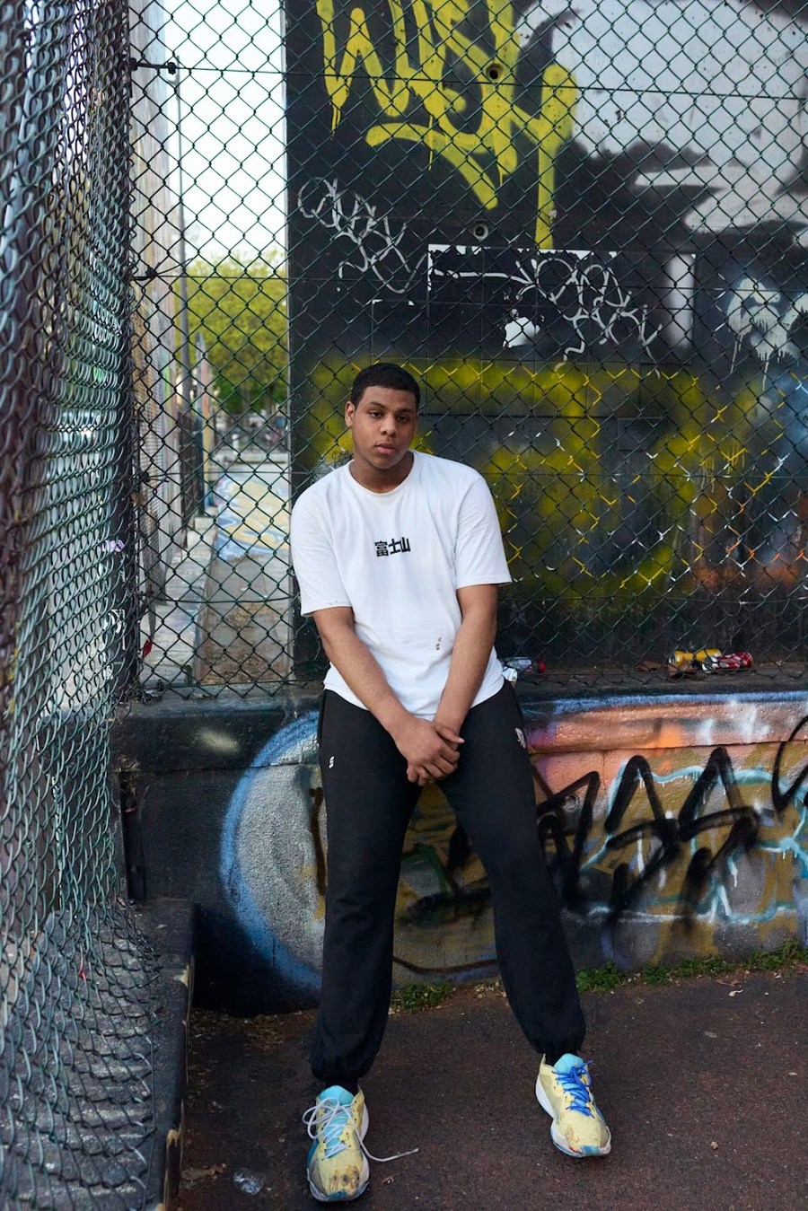 Figure in a white T-shirt beside a graffiti-covered basketball court