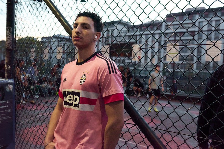 Portrait in a pink football shirt beside the basketball court fence