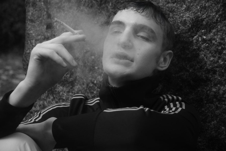 Black-and-white portrait of a smoking figure beneath trees