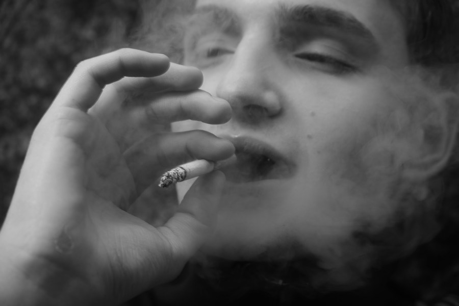 Close black-and-white portrait with a cigarette and drifting smoke