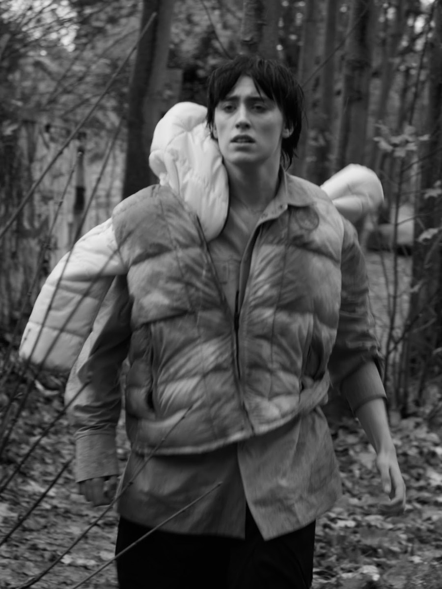 Figure in a padded vest standing among trees