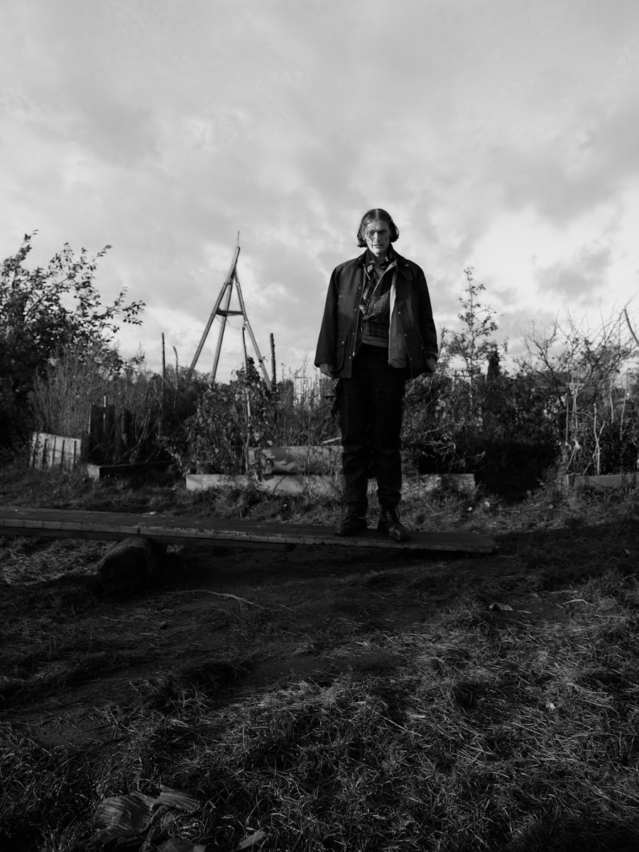 Figure standing beneath a cloudy sky on open ground
