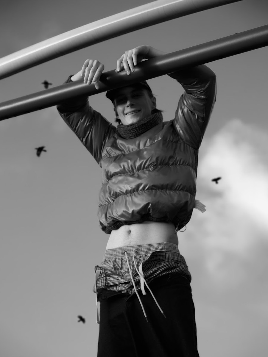 Figure holding overhead metal bars in a padded vest