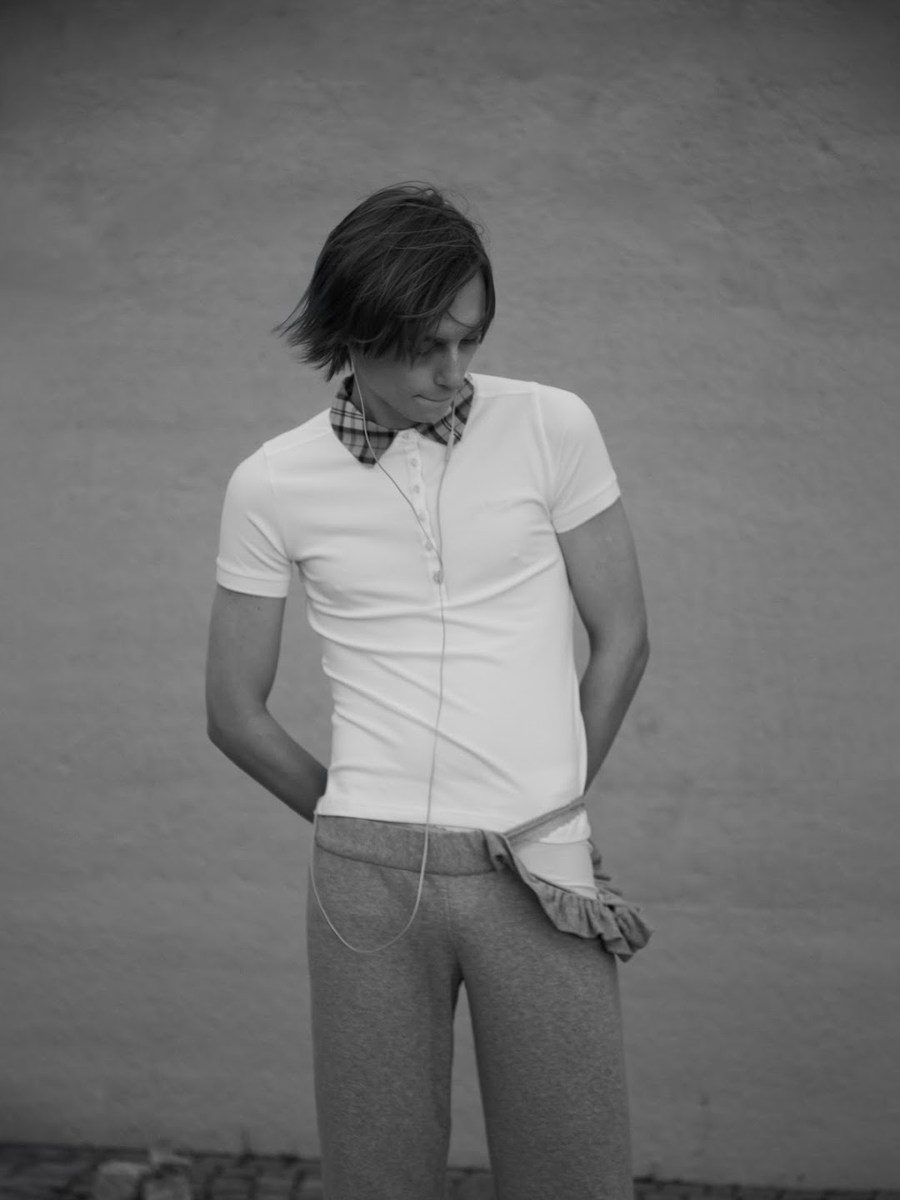 Figure in a white polo shirt against a plain wall