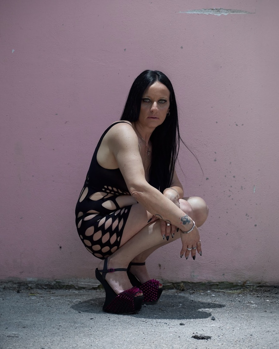 Woman crouching against a pink wall