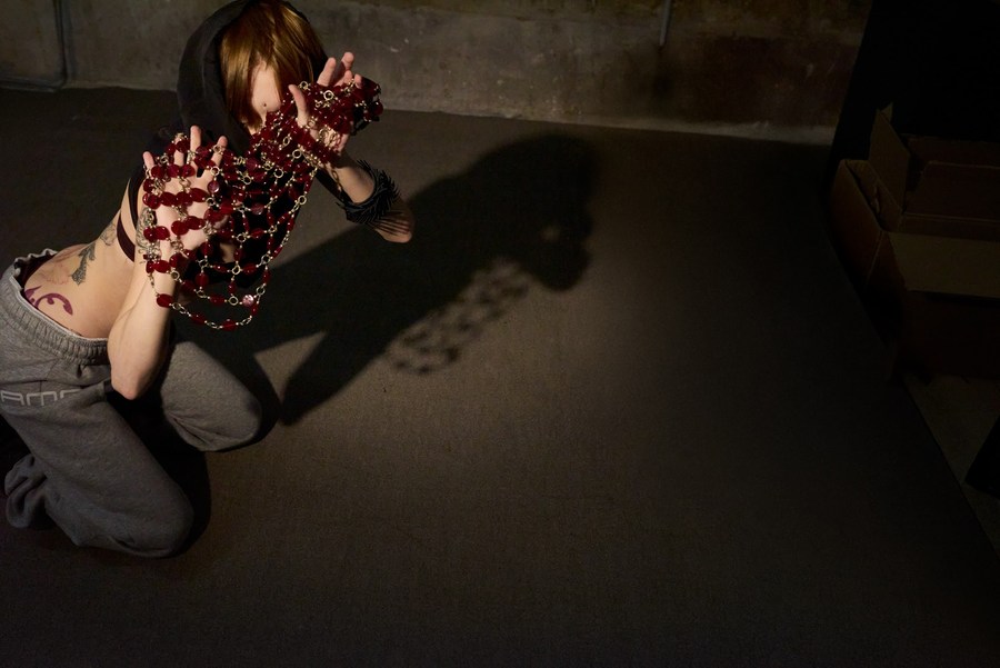 Model reaching towards the camera through red jewels