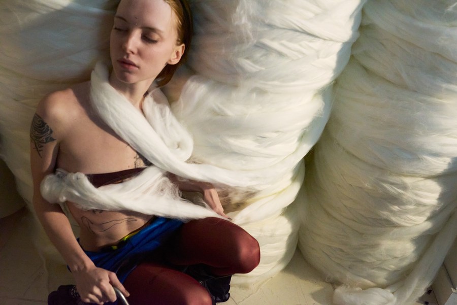 Seated model wrapped in white fabric, with red tights